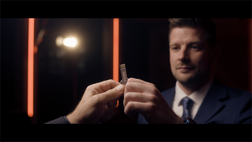 BINA - Mann mit USB-Stich in der Hand und der Aufschrift Erfolg.